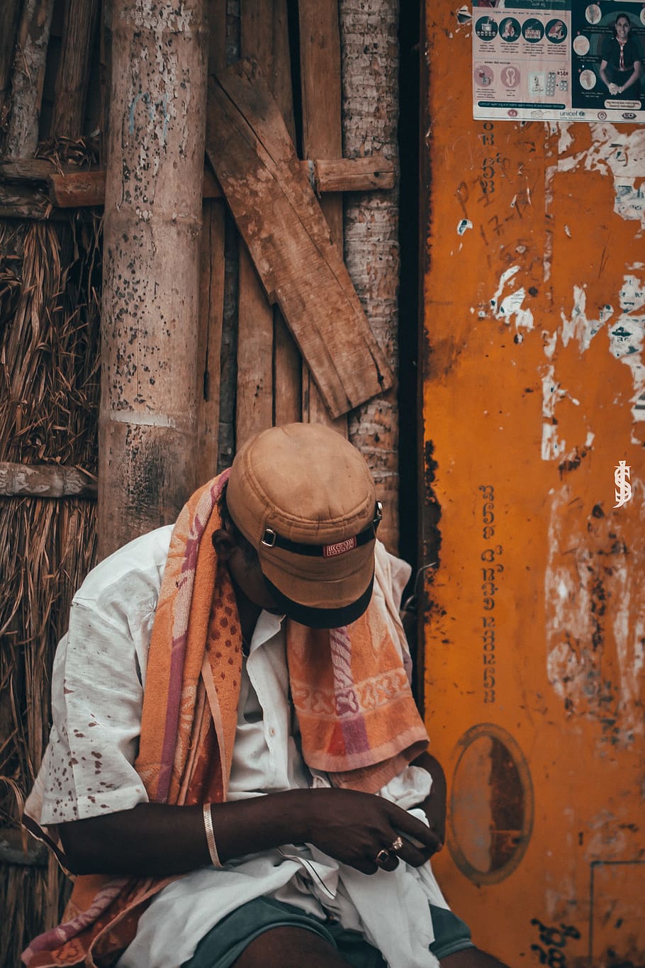 Man in White Top Holding Cloth Beside Brown Wall, bracelet, cap HD wallpaper