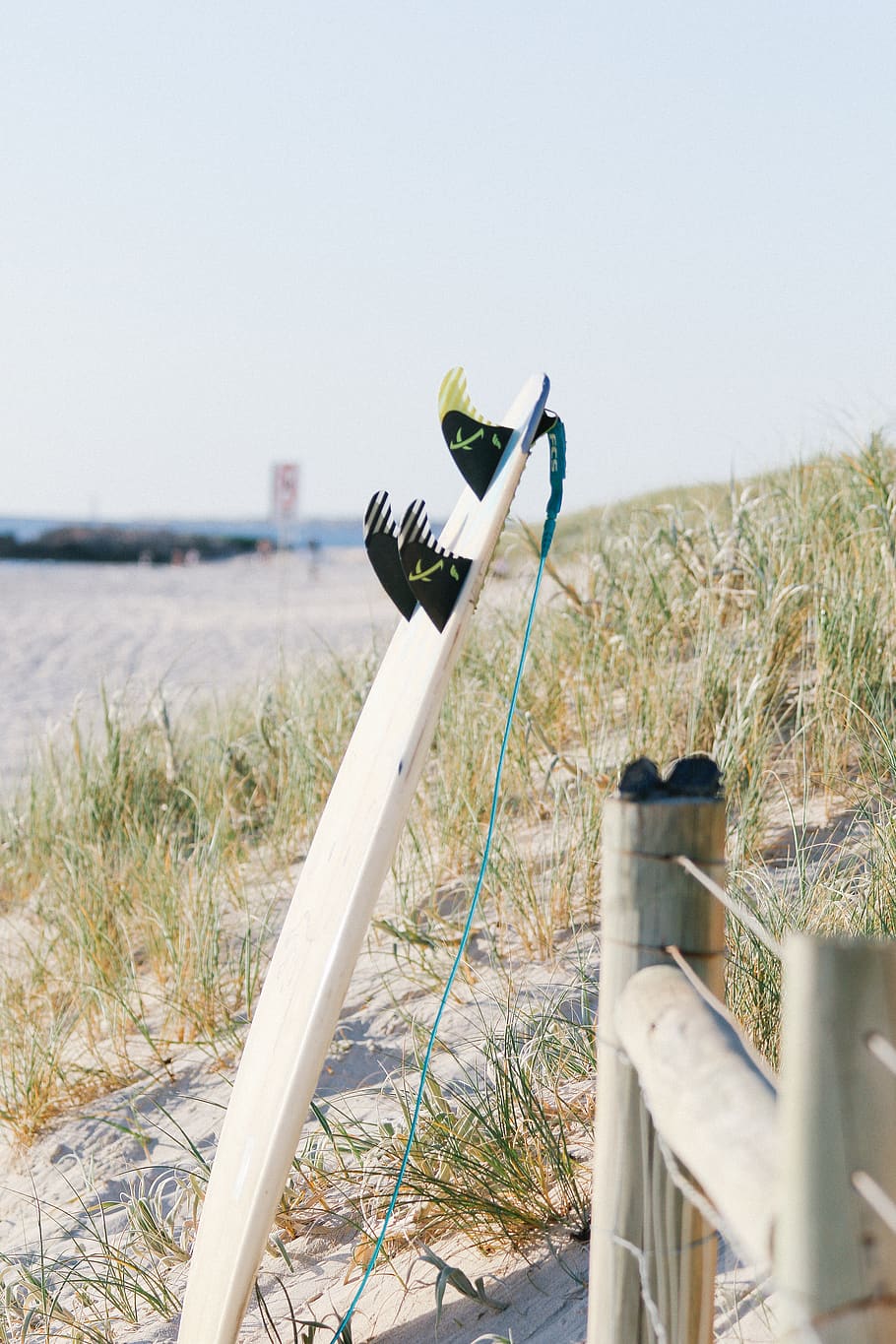 surfboard near post, land, grass, nature, sky, water, day, beach HD wallpaper