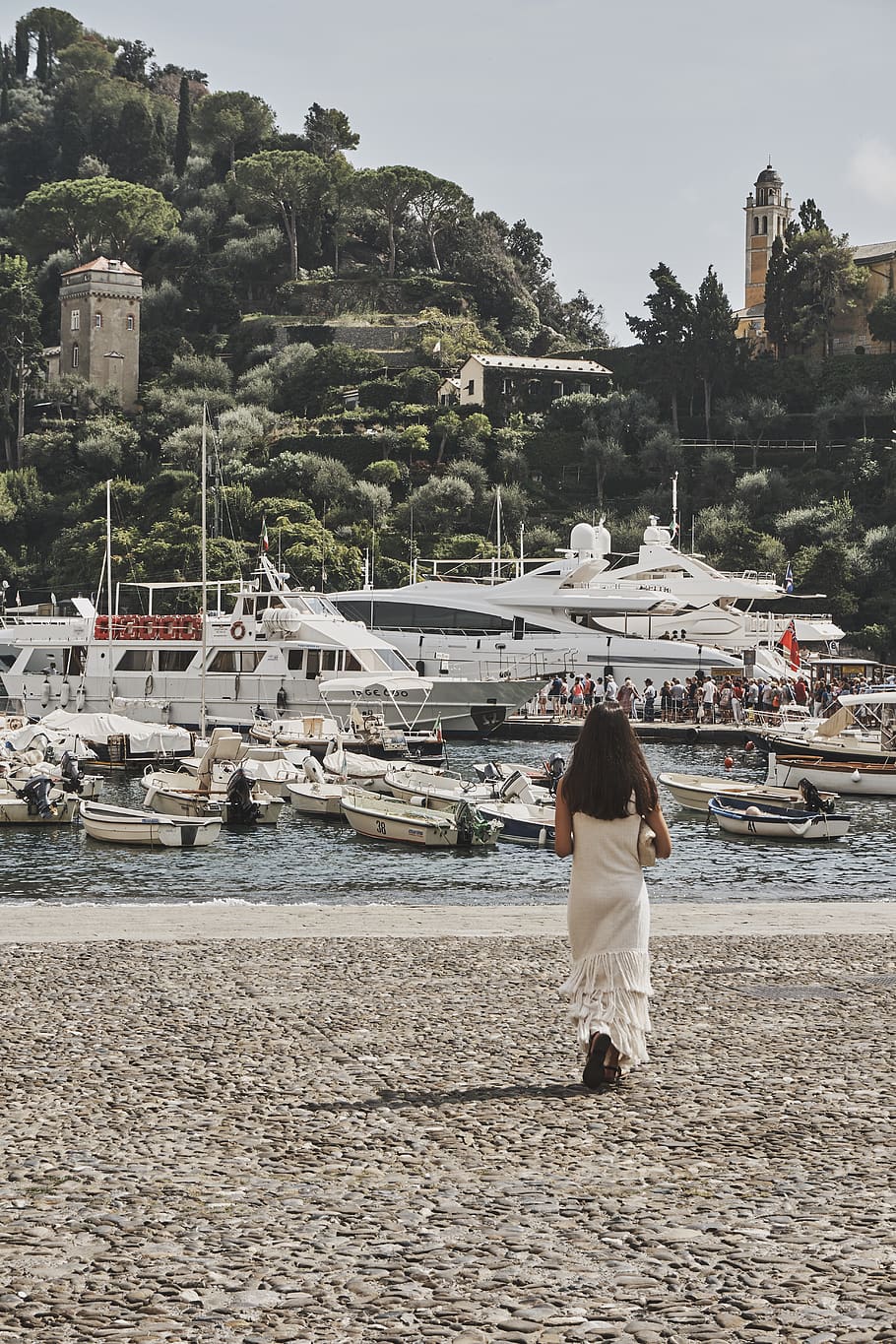 Woman Standing on Brown Ground Beside Body of Water With Assorted Boats and Yacht Under Blue Sky HD wallpaper