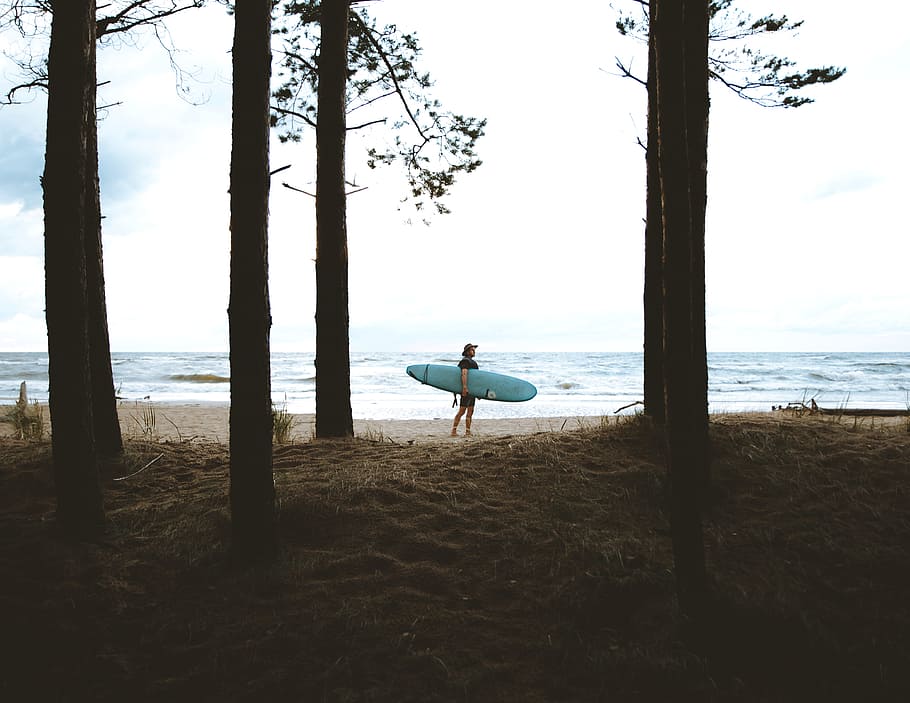 person standing while carrying blue surfboard near sea during daytime, HD wallpaper