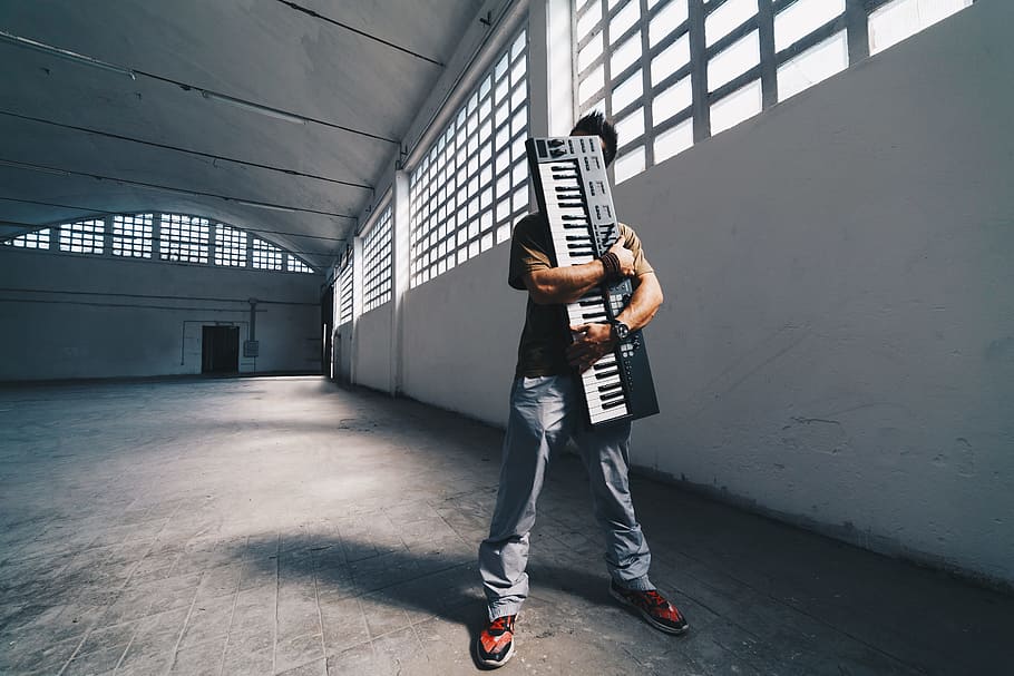 man hugging the electronic keyboard while standing inside room