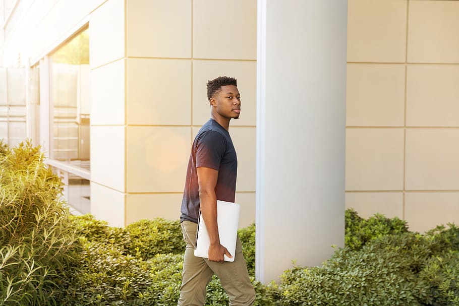 Man Walking Beside Green Leafed Plants Near White Concrete Pillar HD wallpaper