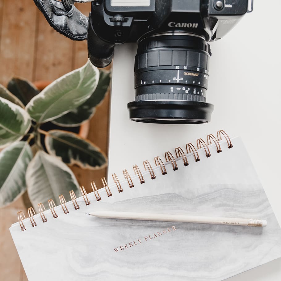 black Canon DSLR camera on table beside notebook, electronics HD wallpaper