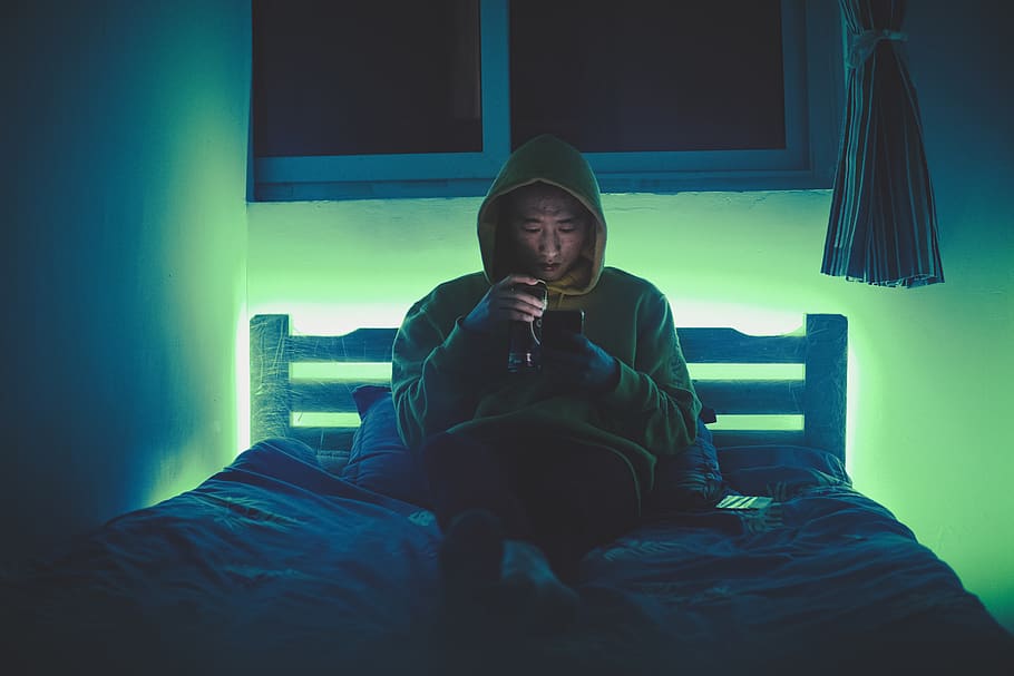 man sitting on bed while using smartphone, one person, indoors HD wallpaper