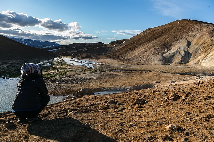 Person Squatting Front of Brown Mountain, clouds, daylight, environment HD wallpaper