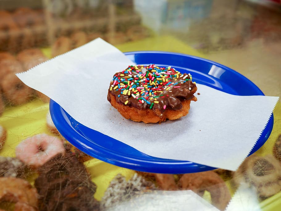 Cake donut with sprinkles and chocolate icing on a blue plate. HD wallpaper