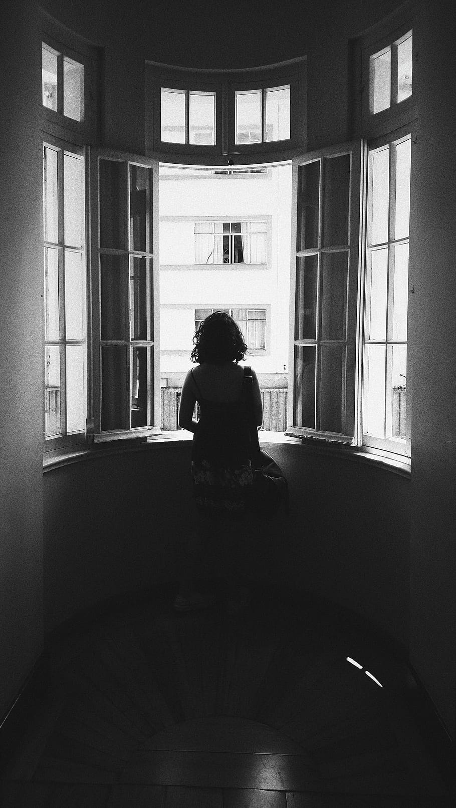 grayscale photo of woman standing in front of window, person