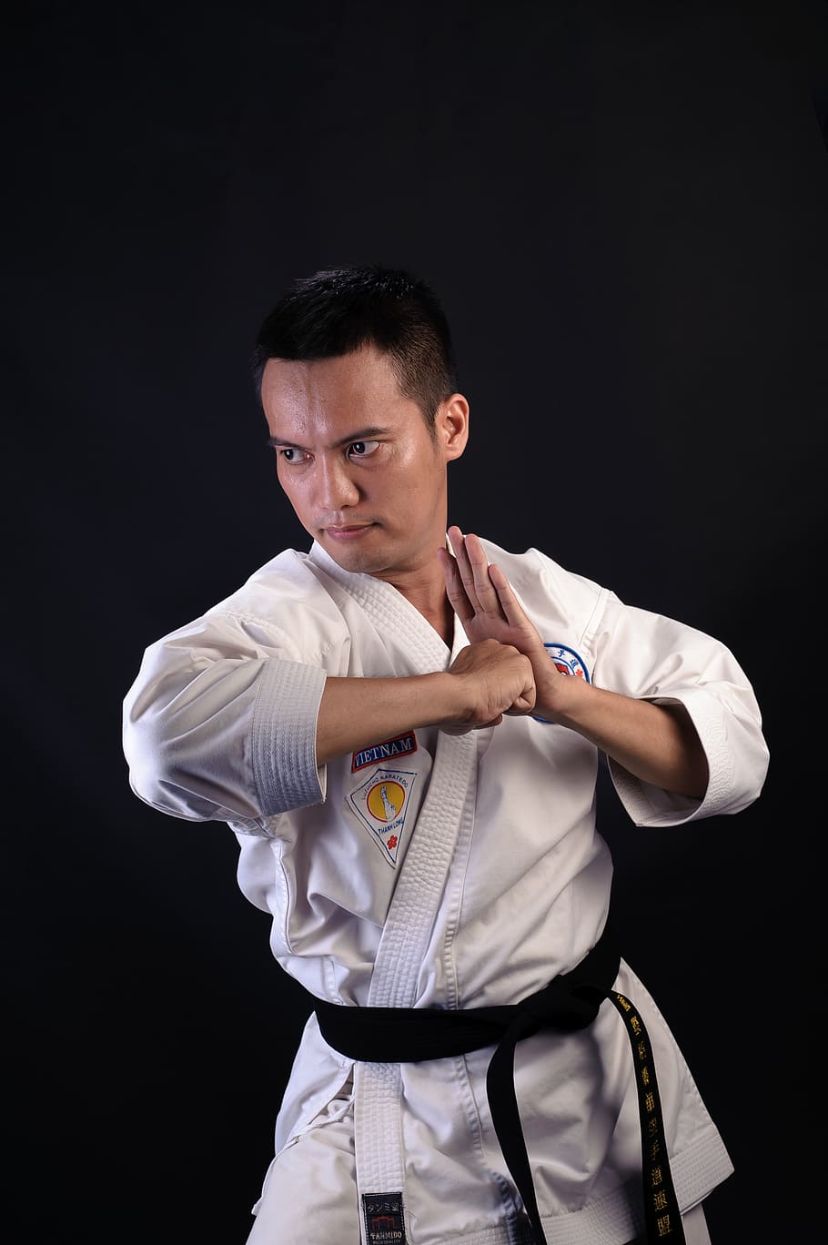 man in karate gi outfit, studio shot, black background, one person