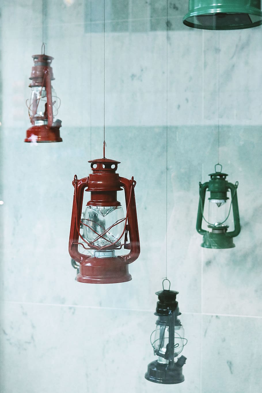 Four Assorted-color Metal Gas Lanterns Hanging Near Tile Wall HD wallpaper