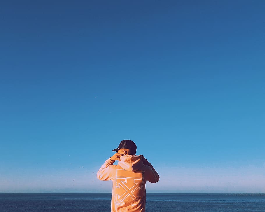Man Holding His Hood, beach, beautiful, blue sky, cap, color HD wallpaper