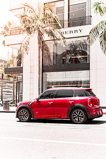 red 5-door hatchback in front of Burberry building, palm tree HD wallpaper