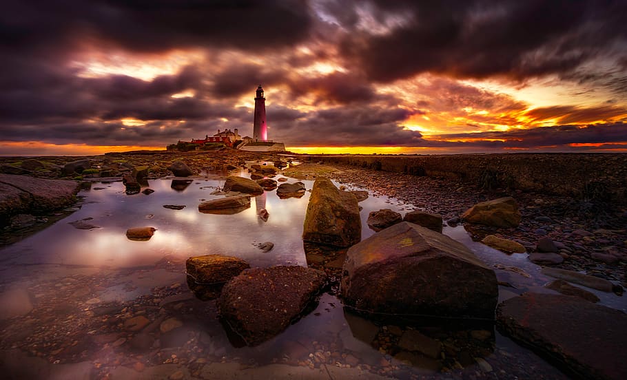 Rocks on Body of Water Near Lighthouse during Golden Hour, clouds HD wallpaper