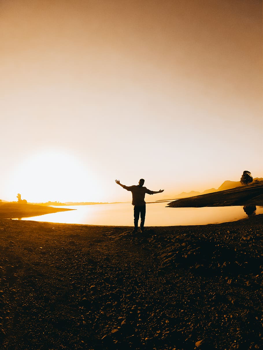 Silhouette Of Person Standing Near Body Of Water During Golden Hour HD wallpaper