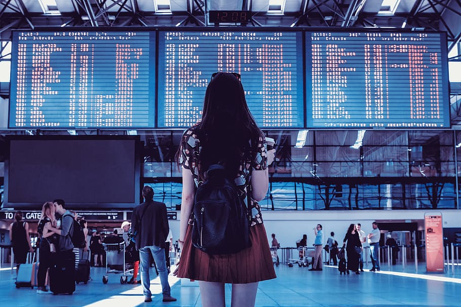 Young woman with bag checking flight timetable in international airport HD wallpaper