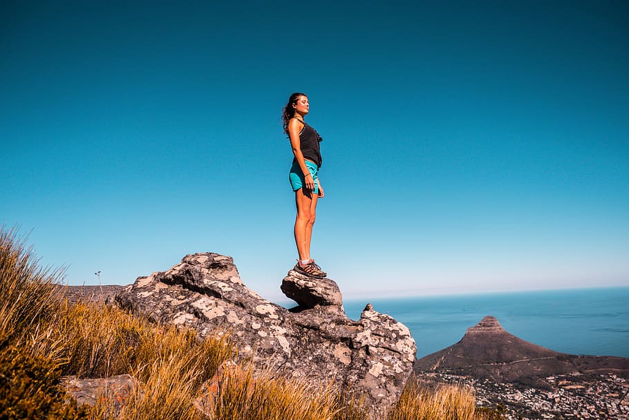 Woman in Black Top and Blue Shorts on Stone Under Blue Sky, adventure HD wallpaper