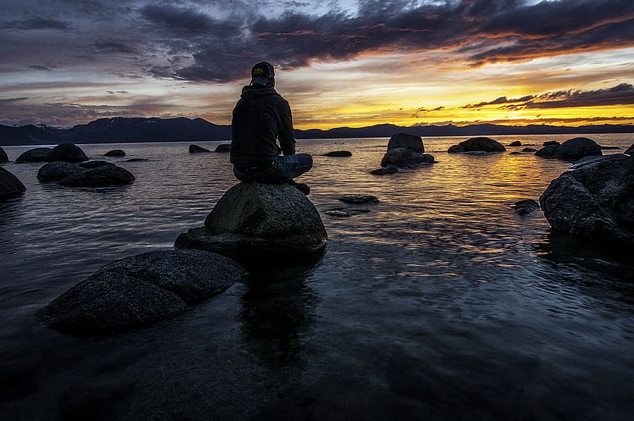 Person Sitting on Rock on Body of Water, beach, cap, clouds, coast HD wallpaper