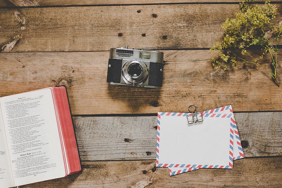 gray and black camera beside open book, green leafed plant, and white airmail envelopes HD wallpaper
