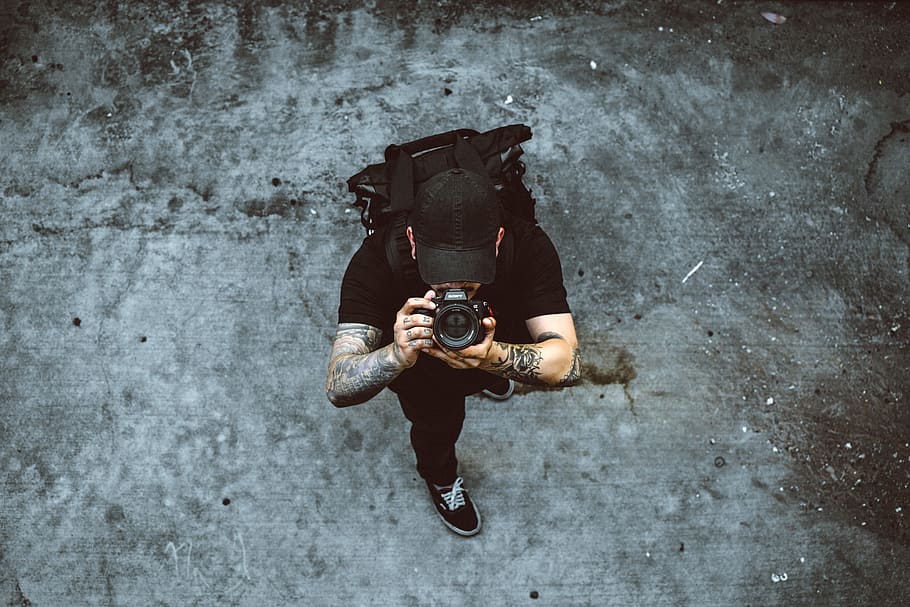 man taking photo while standing on gray concrete ground, photography