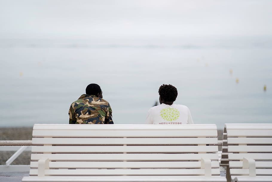 two men sitting on bench facing sea, person, outdoor, ocean, looking out