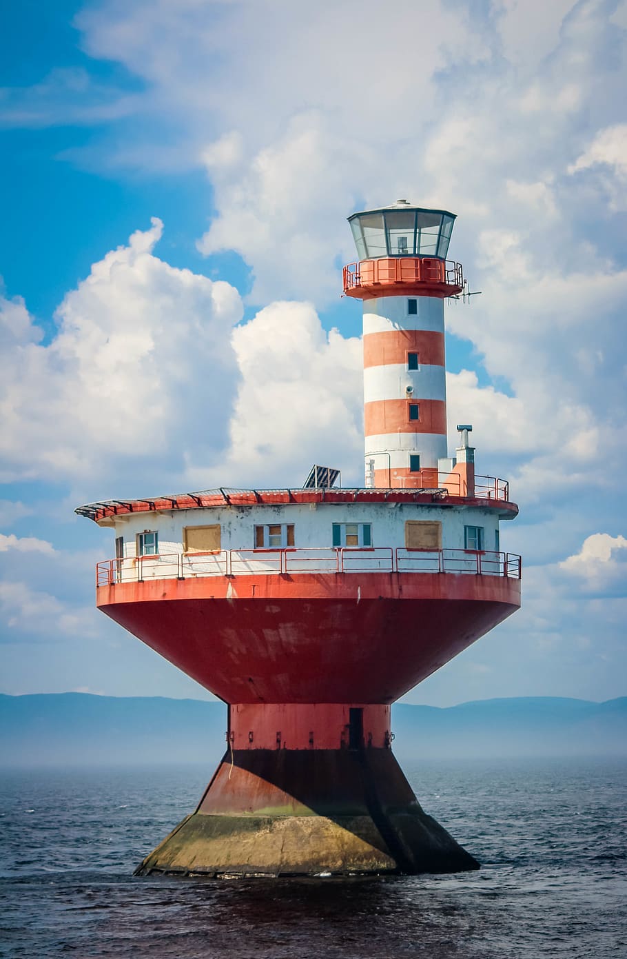 red and white concrete lighthouse surrounded body of water during daytime