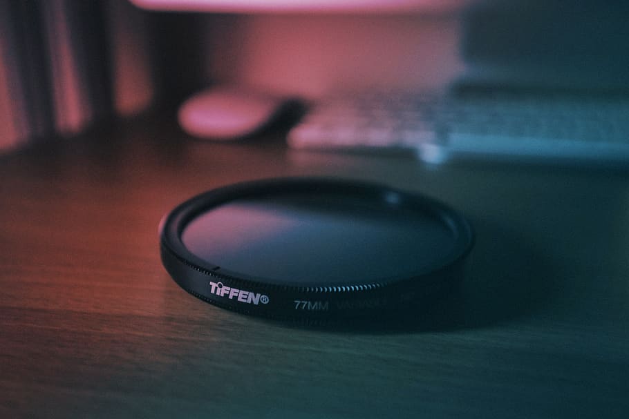round black Tiffen cover near white computer keyboard, lens cap