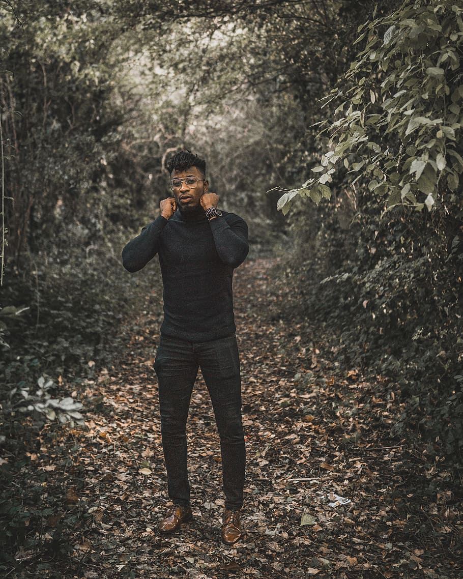 standing man wearing black turtleneck sweater and black fitted pants surrounded with trees during daytime HD wallpaper