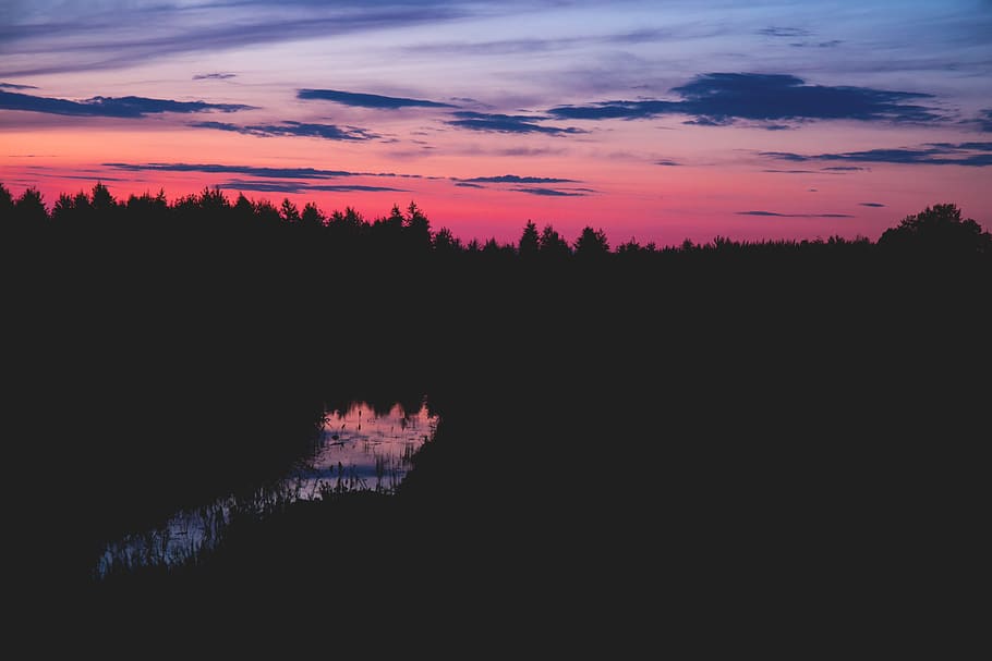 Body of Water Between Silhouette of Trees Under Red Black and Grey Sky at Sunset HD wallpaper