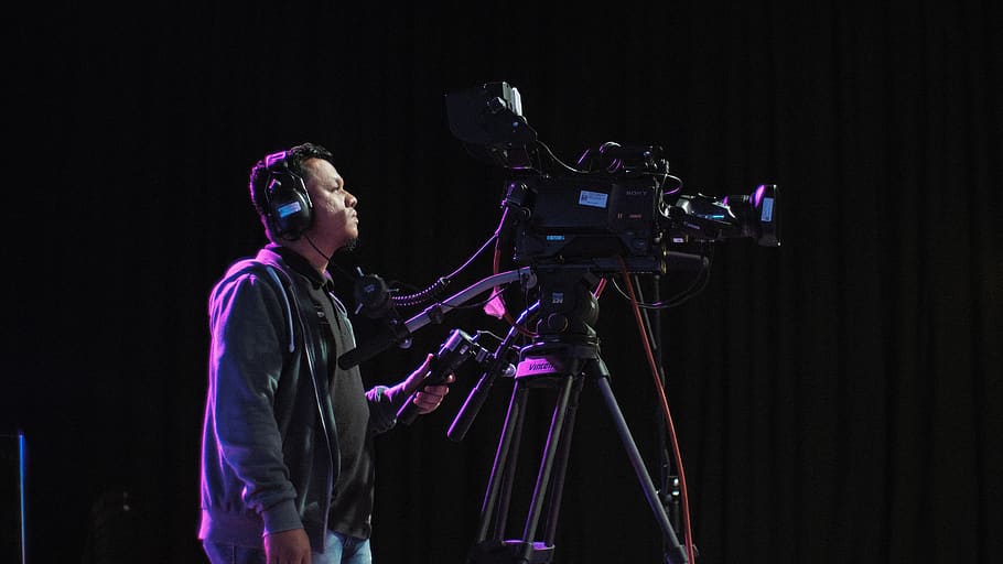 cameraman operating black camera inside room, one person, black background HD wallpaper
