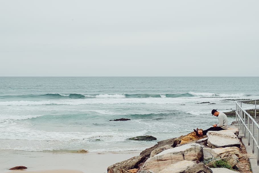 Man Sitting On Rocks, beach, ocean, person, relaxation, sea, seashore HD wallpaper