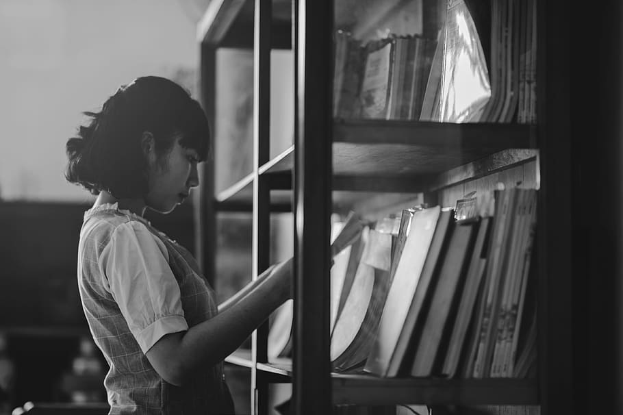 Grayscale Photo of a Woman Holding a Book Inside the Library, HD wallpaper
