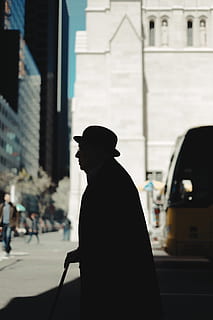 silhouette of man holding walking cane on road during daytime HD wallpaper