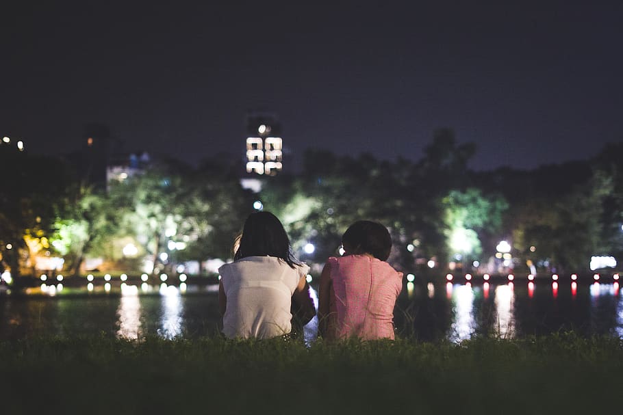 Couple Sitting on Grass in Front of Body of Water, girls, lights HD wallpaper