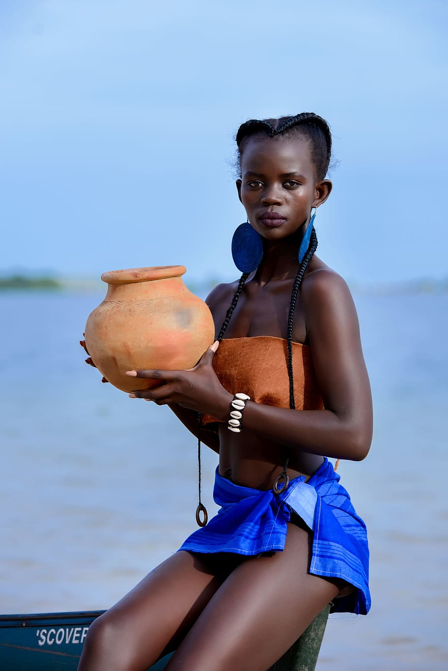 Woman Sitting on Boat Holding Brown Clay Pot, beach, braided hair