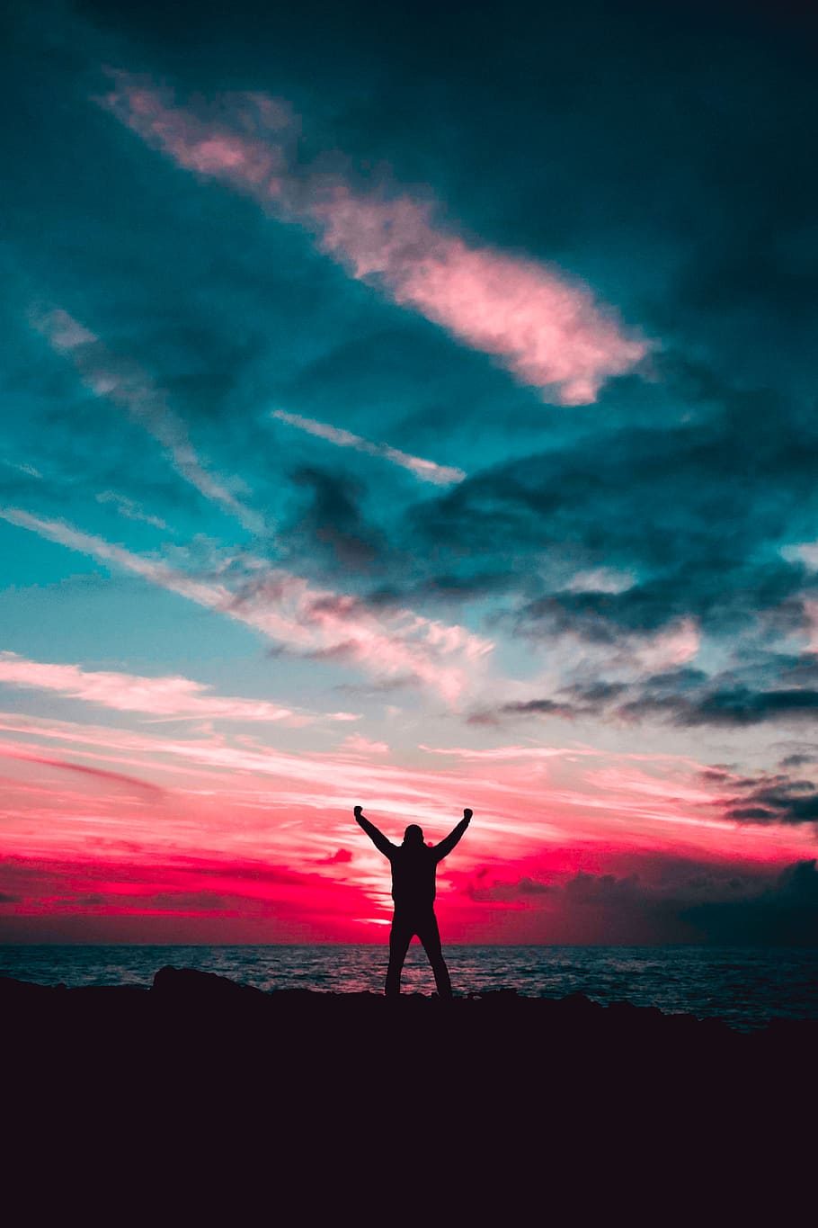 Silhouette of Man Raising Hands Against a Red Sunset Light Under Green Clouds HD wallpaper