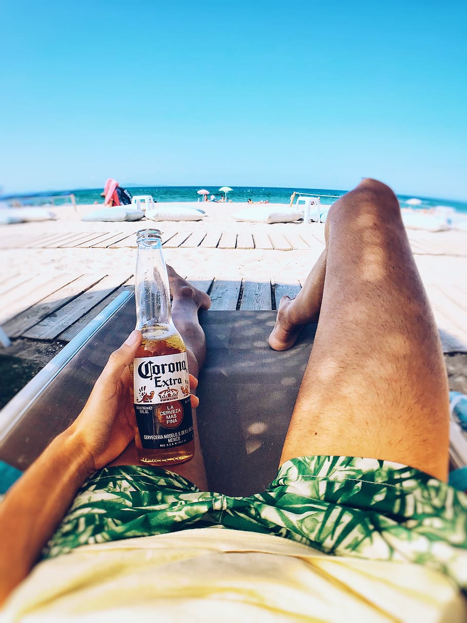 Person Laying On Lounge Chair Holding Corona Bottle, beach, beer