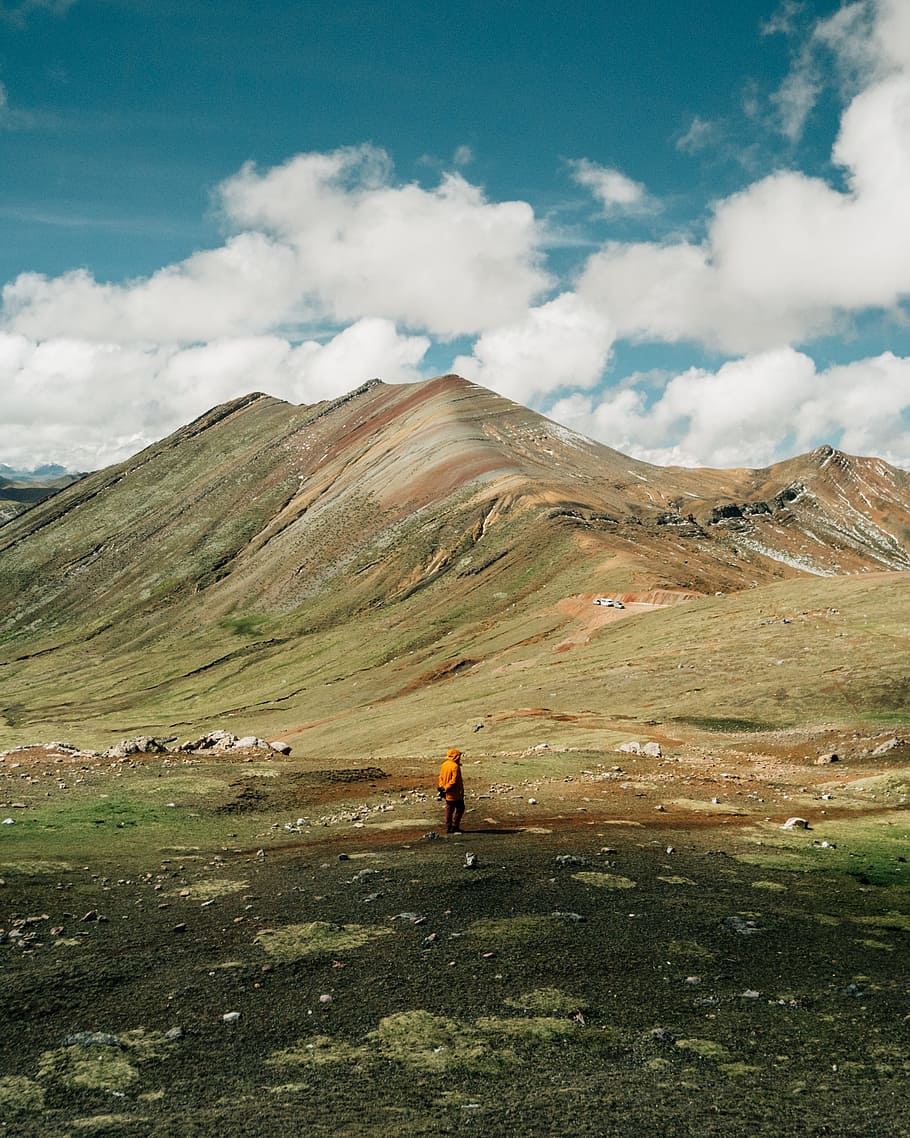 man standing on green grass field near mountain ridge, person HD wallpaper