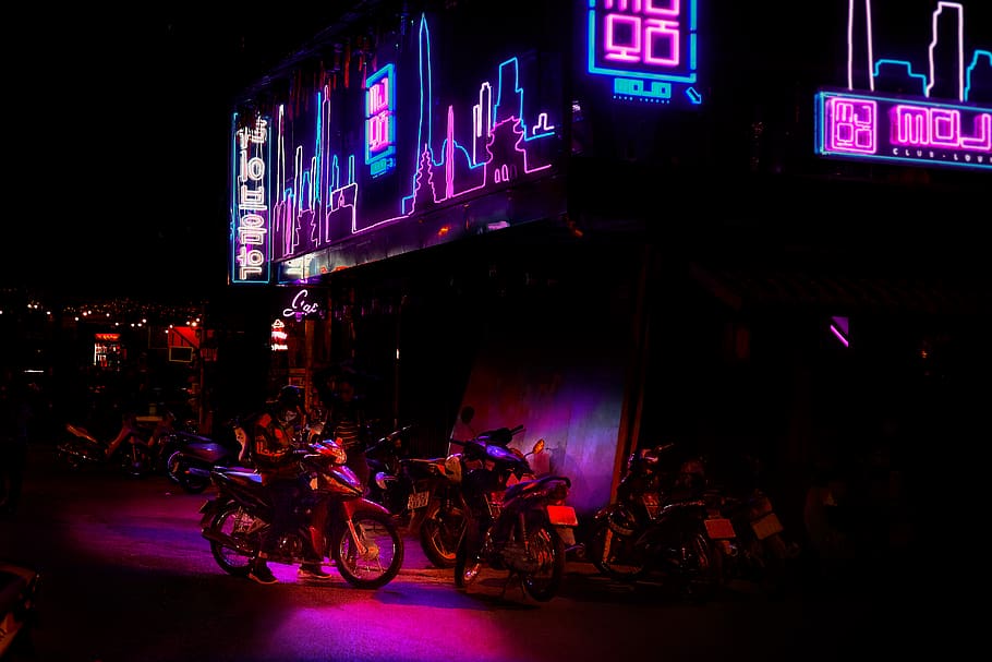 motorcycles park under blue and pink LED signage, transportation