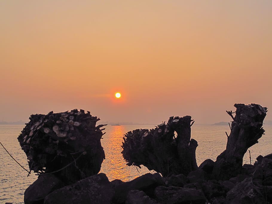 sunset, water, orange, haze, rock, sky, rock - object, solid HD wallpaper