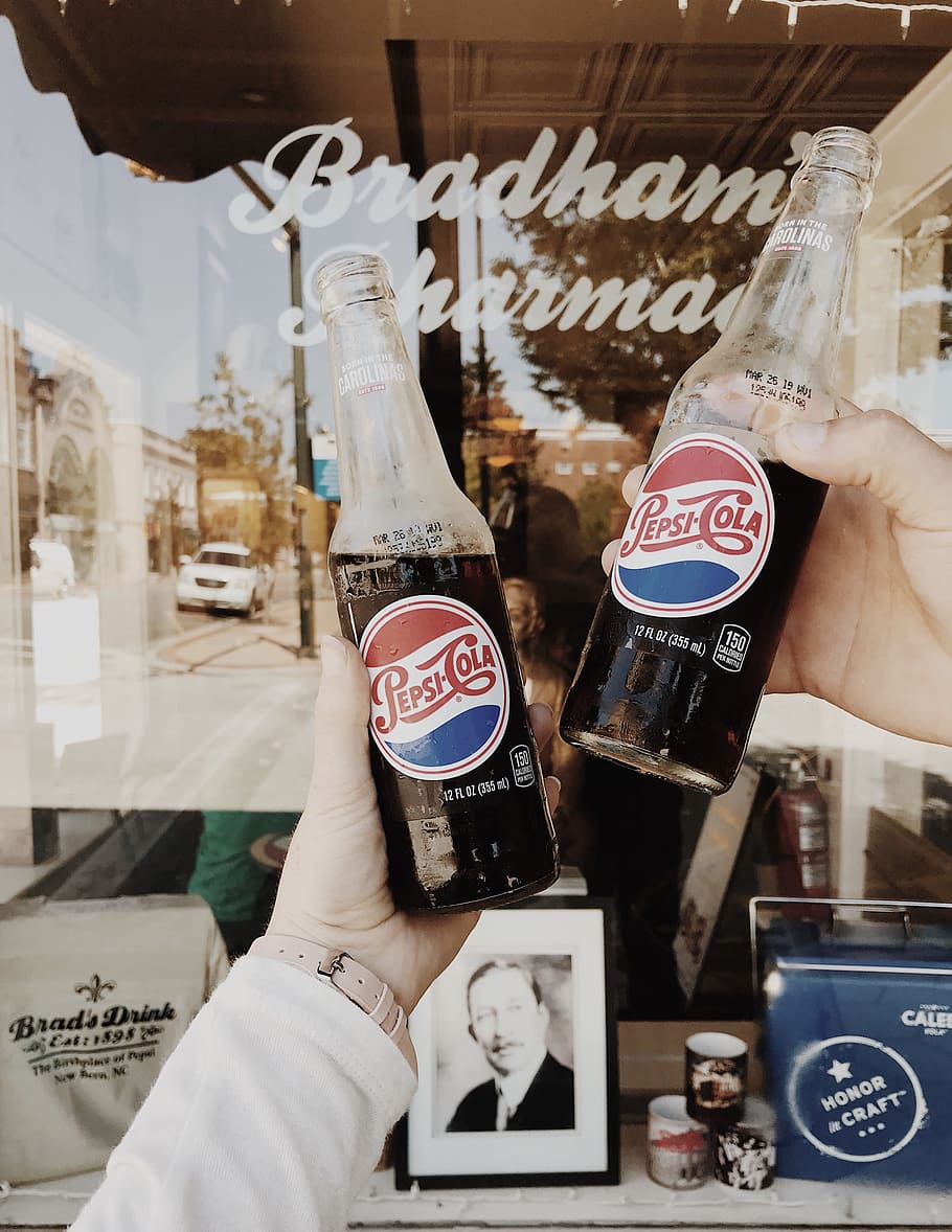 person holding Pepsi Cola soda bottles, pop, window, cheers, closeup