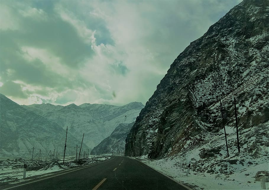 Snow Covered Mountain Ranges Near the Asphalt Road Under the Cloudy Sky HD wallpaper