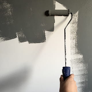 Person Holding Paint Roller While Painting the Wall, daylight HD wallpaper