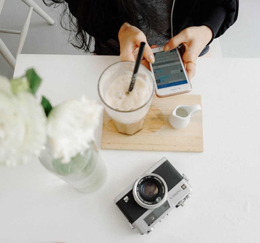 person sitting using iPhone near table with camera on table, mobile phone HD wallpaper