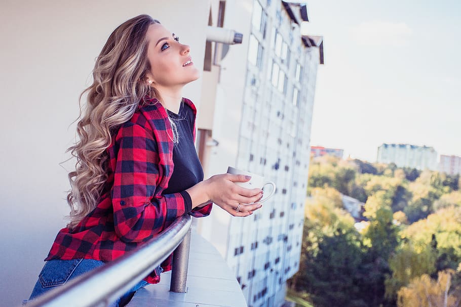 woman looking up while leaning on balcony of a building, person