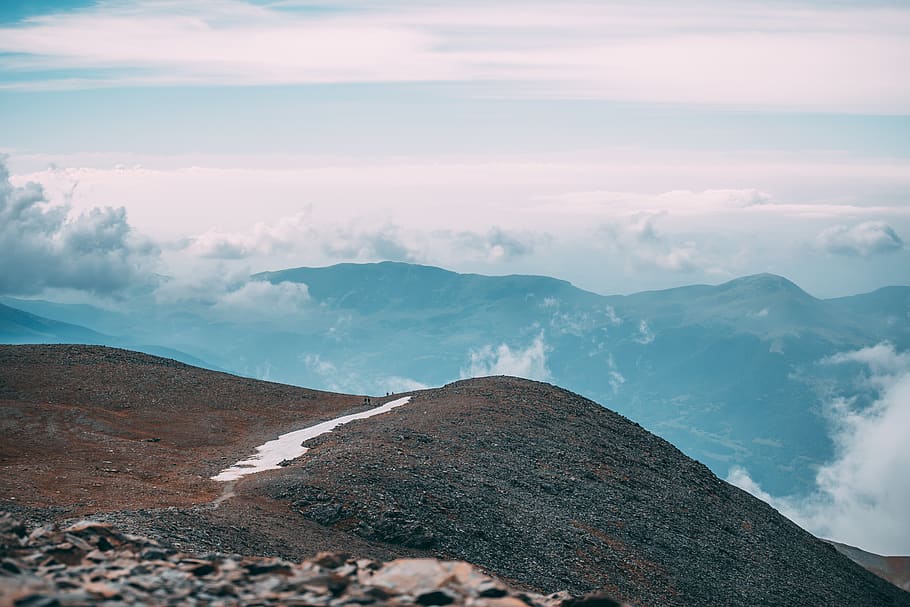 cliff overlooking clouds surrounding mountain during daytime HD wallpaper
