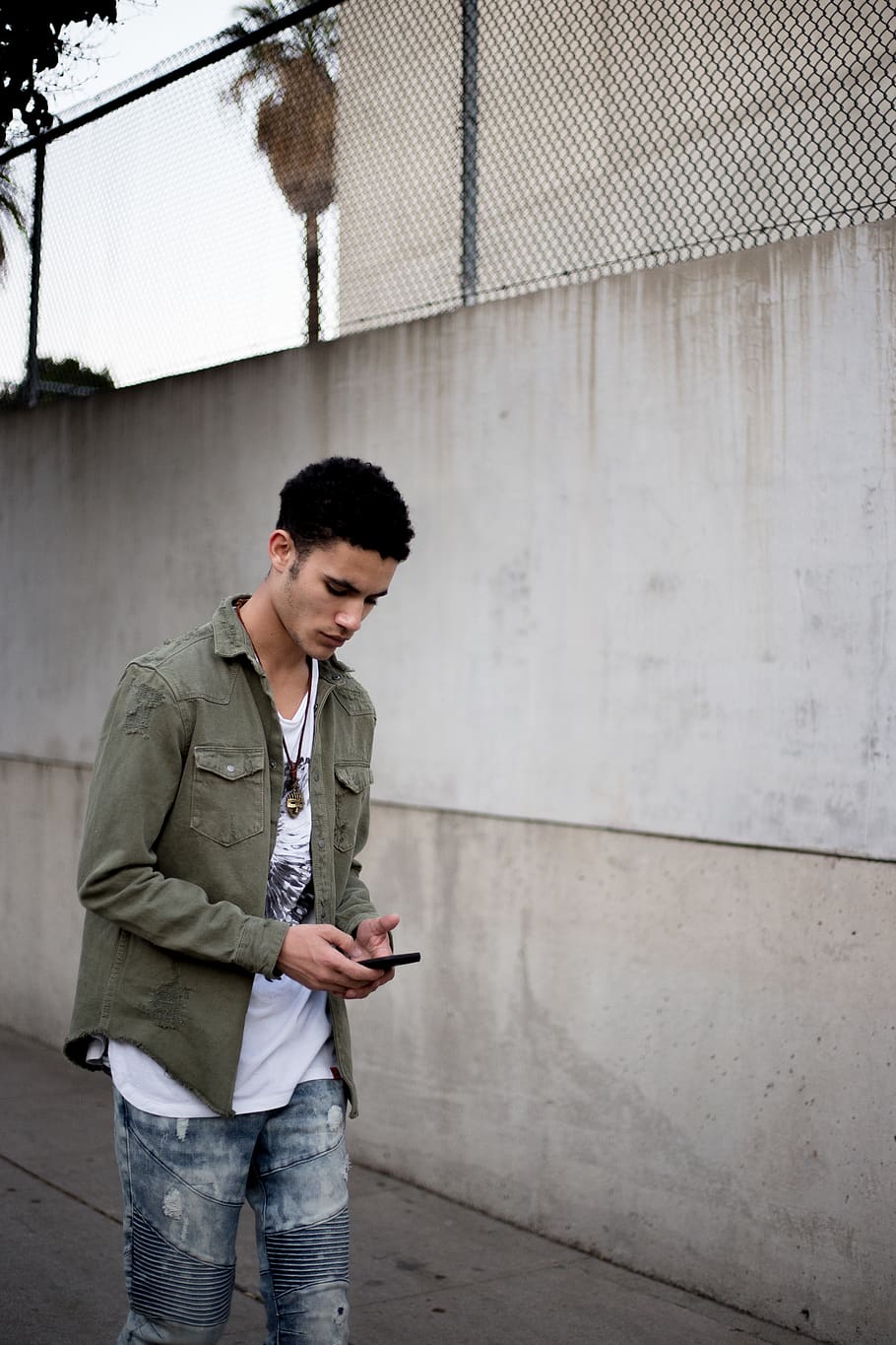 man looking down while holding phone near wall, young adult, one person HD wallpaper