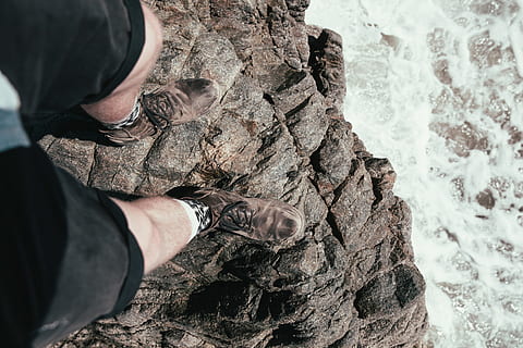 Feet hanging over the edge of a rock with seawater in the background HD wallpaper