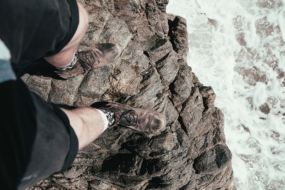 Feet hanging over the edge of a rock with seawater in the background HD wallpaper