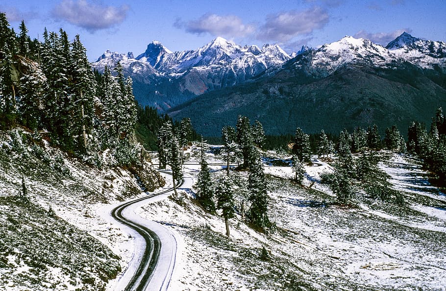View of road between snow capped mountains and trees, cloud, clouds HD wallpaper