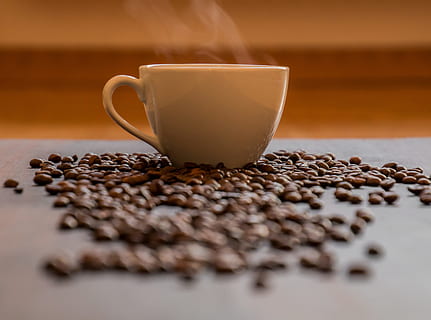 White Ceramic Teacup With Smokes Surrounded by Coffee Beans in Selective Focus Photography HD wallpaper