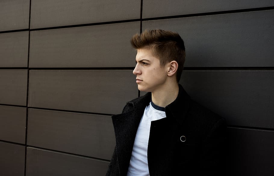 man leaning on gray wall, apparel, clothing, person, human, coat HD wallpaper